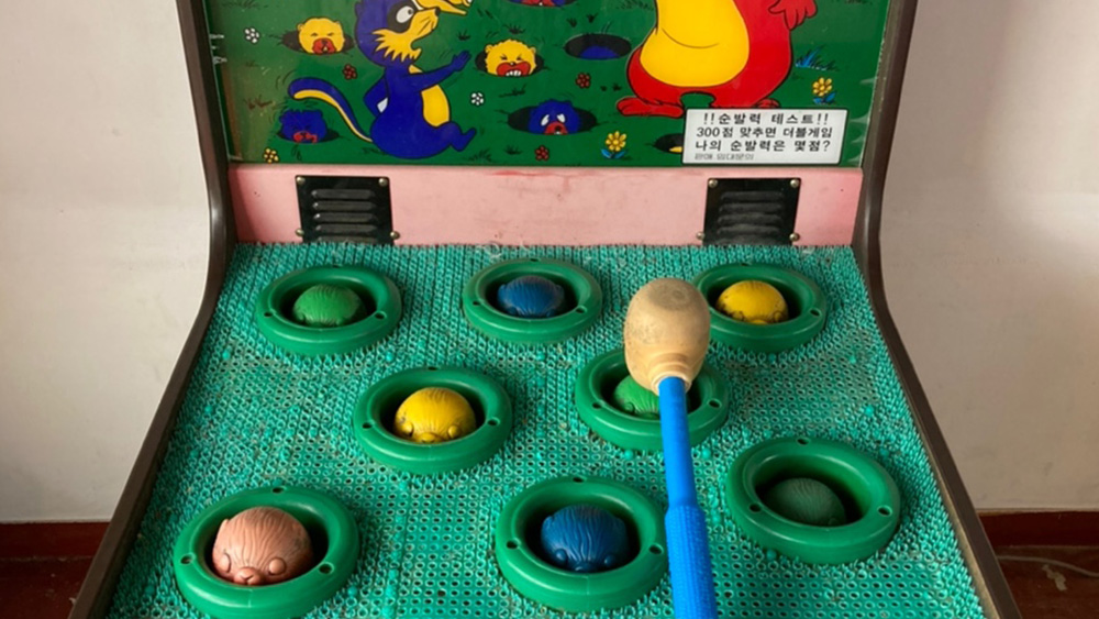 두더지잡기 게임기 위에 게임망치를 올려놓은 모습을 측면에서 찍은 사진