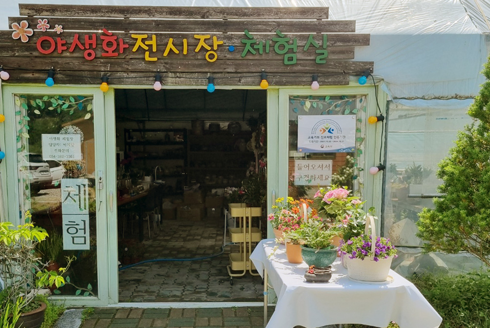야생화 전시장/체험실에서 나오고 있는 5명의 어른과 1명의 아이의 사진